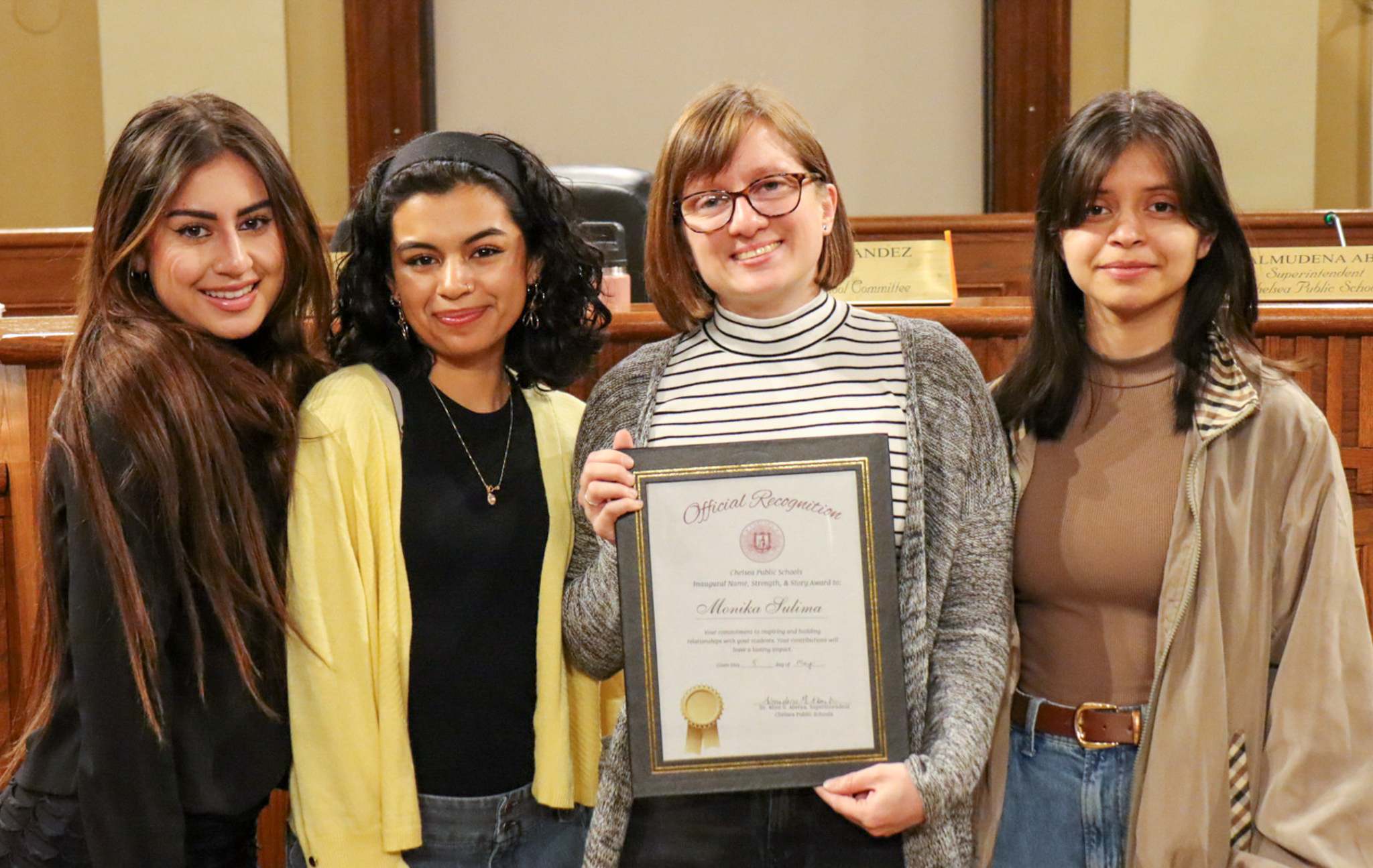 Monika Sulima holding a certificate for her Name, Strength Story award. She is standing with three CHS students.